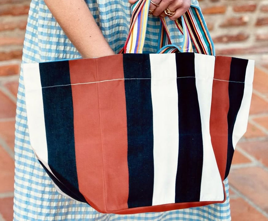 Carry bag made from Les Toiles du Soleil Carthage Tomette fabric. Featuring bold black and ecru/beige stripes in-between red edges