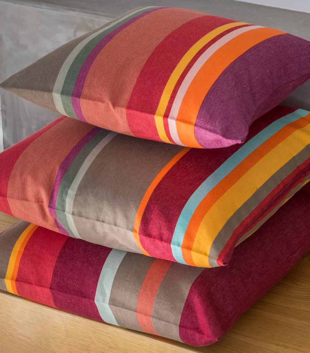 Stack of 3 cushions made from Collioure Rouge a Les Toiles du Soleil striped indoor fabric in red, orange, and yellow