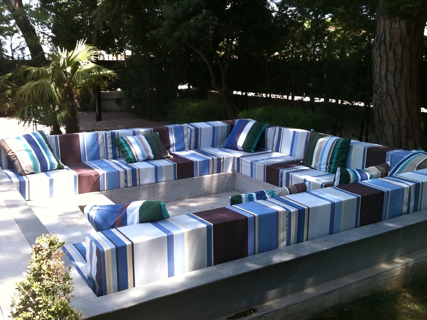 Outdoor patio furniture set with Les Toiles du Soleil Cyprian Outdoor Sunbrella Fabric striped cushions on a patio area.