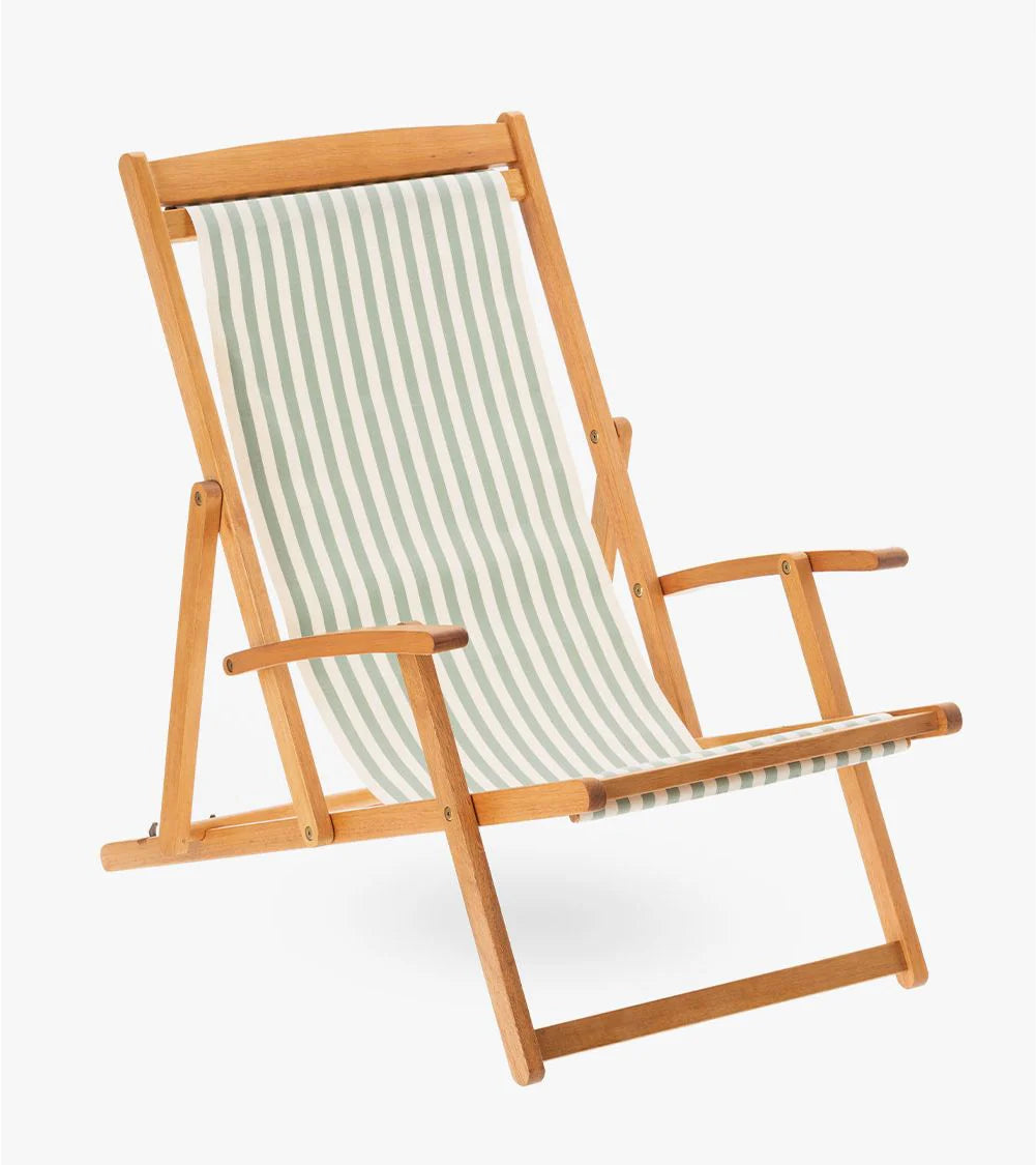 Wooden deckchair with cotton fabric featuring even stripes of soft sage/almond green and crisp white. Made by Les Toiles du Soleil. On white background