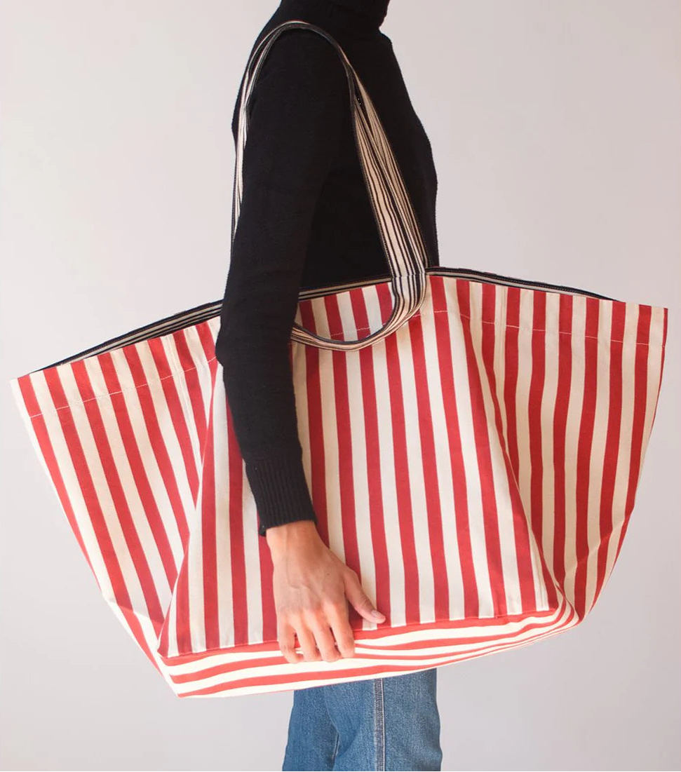 Person from shoulders down showcasing an extra large shoulder carry bag made from Les Toiles du Soleil Canisse Tomette Cotton fabric featuring stripes of ecru and tomette/ tomato terracotta