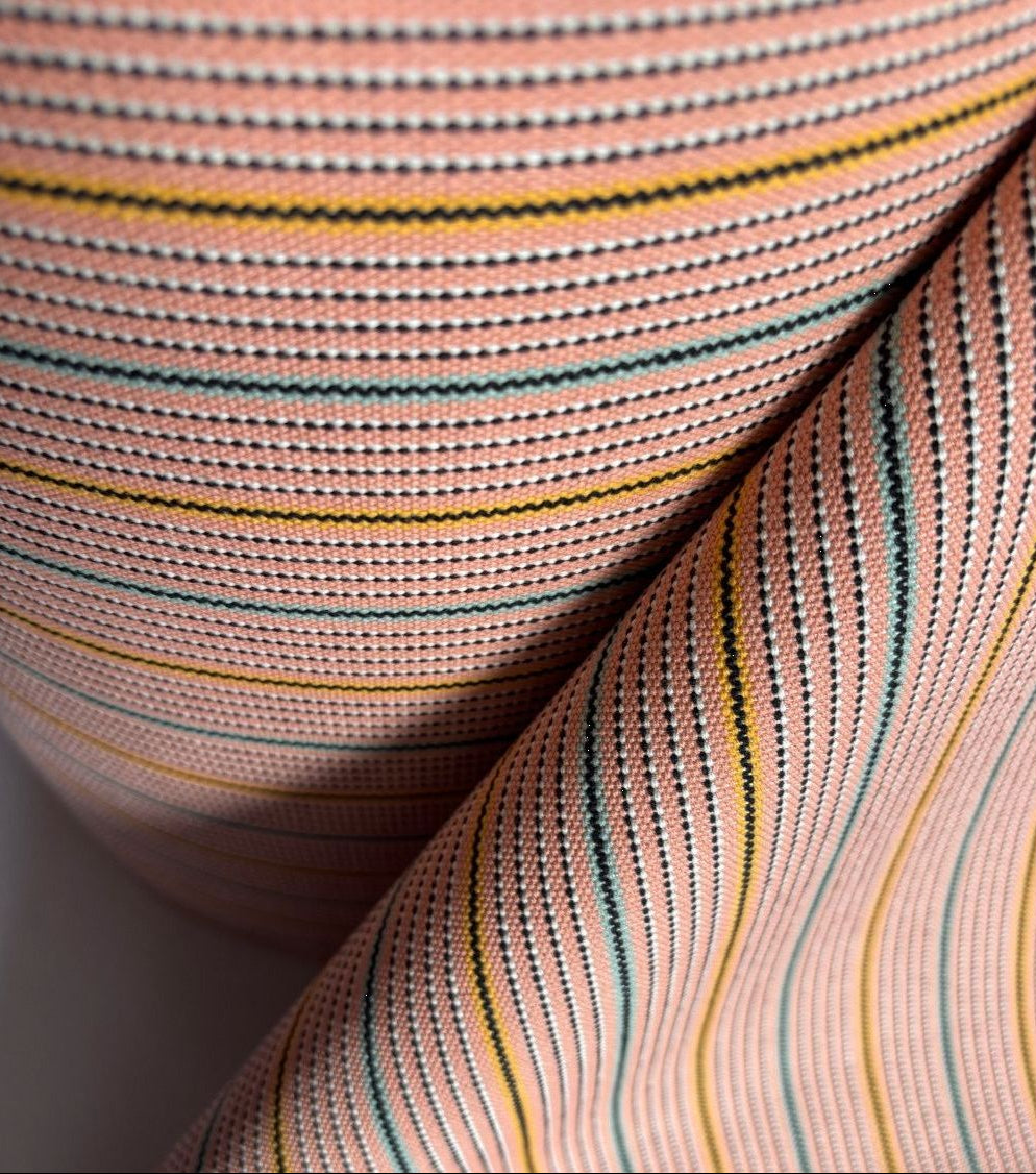Close-up of the 1897 No.1 fabric roll showing woven vertical stripes in soft pink, red, beige, and cream tones with a textured linen-cotton weave. Made by Les Toiles du Soleil