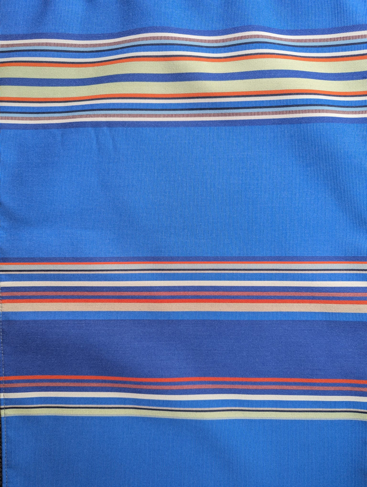 close up of  outdoor Sunbrella and Les Toiles du Soleil fabric. Showing multi-coloured stripes of blues, beige, green, orange and red.