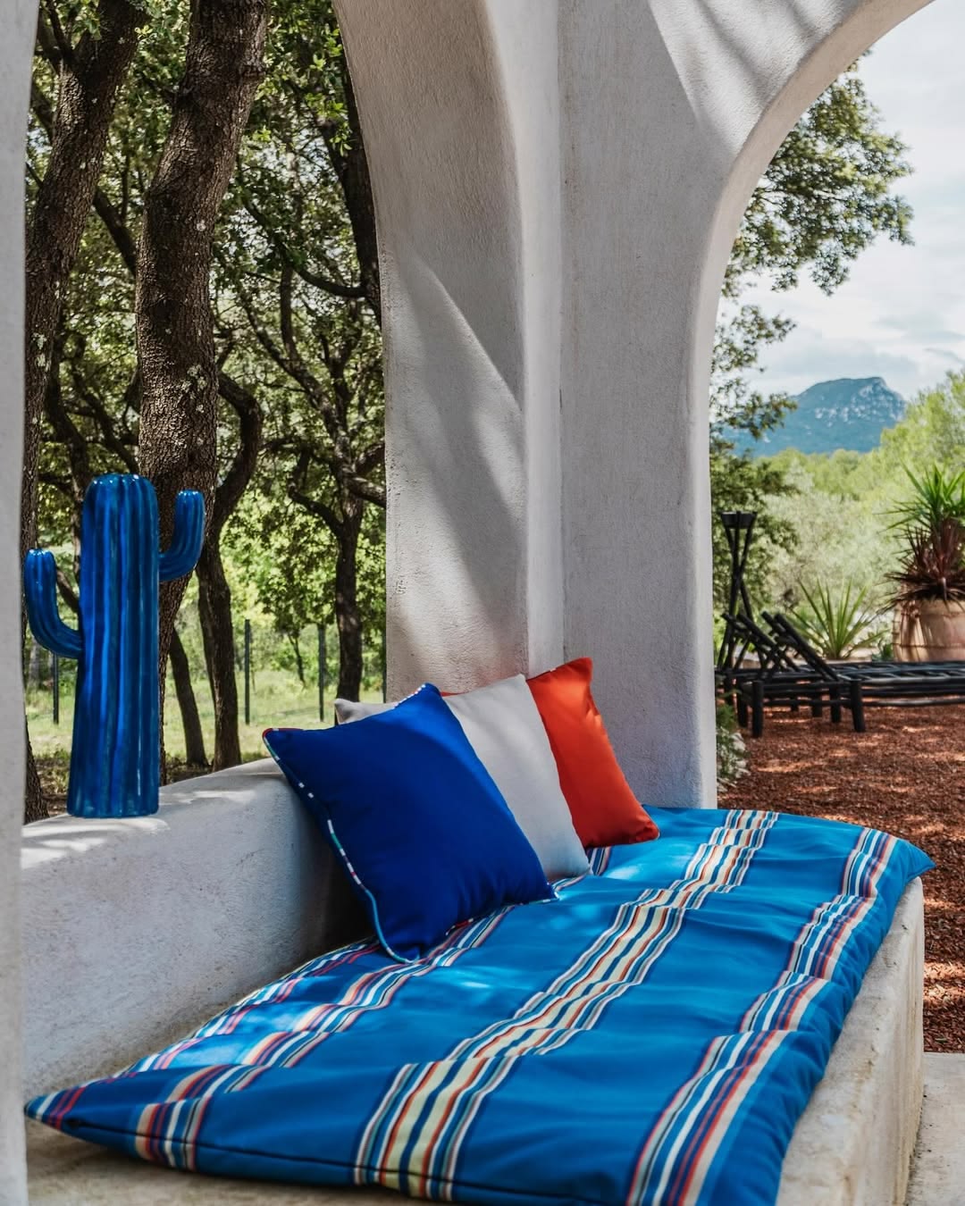 Outdoor seating arrangement with cushioned mattress made from sunbrella Alexandre blue and other coloured striped fabric