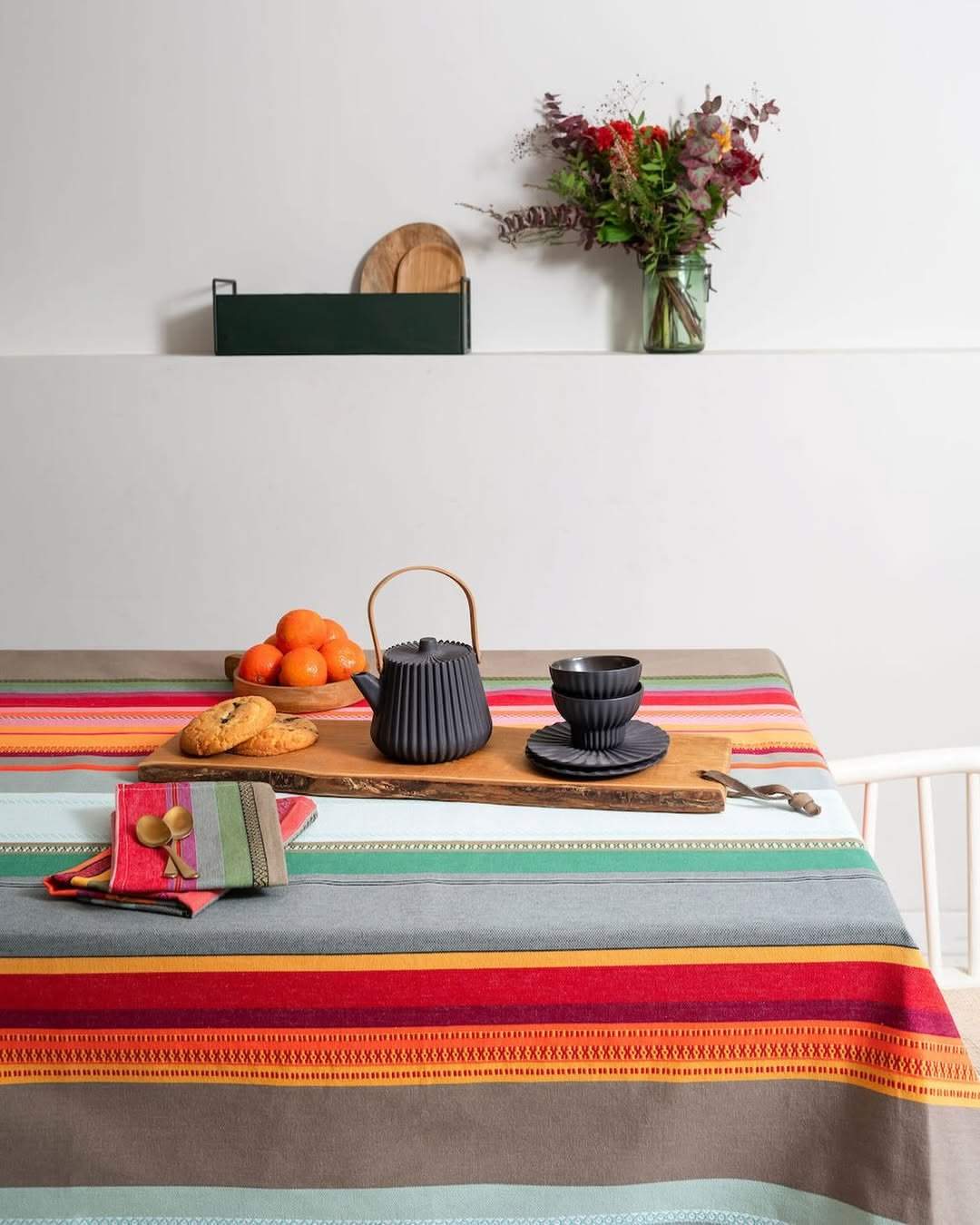 Les Toiles du Soleil Arles sur Tech multi coloured grey, red, yellow and orange fabric table cloth and dining setting.
