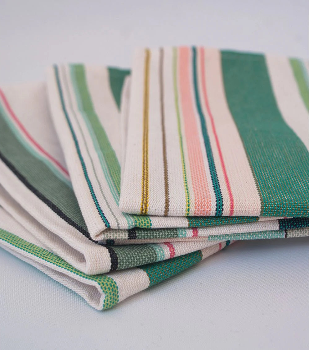 Close up of Les Toiles du soleil Bompas range of indoor cotton fabric roll. This multi coloured striped fabric palette is made up of greens, light blues, soft pinks and white 