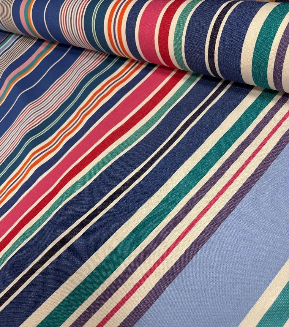 Close up of cotton fabric range-Aigue Marine, which is a multi coloured striped fabric made by Les toiles du Soleil. It showcases a variety of shades of blue, pink, red turquoise, greens and other vibrant colours
