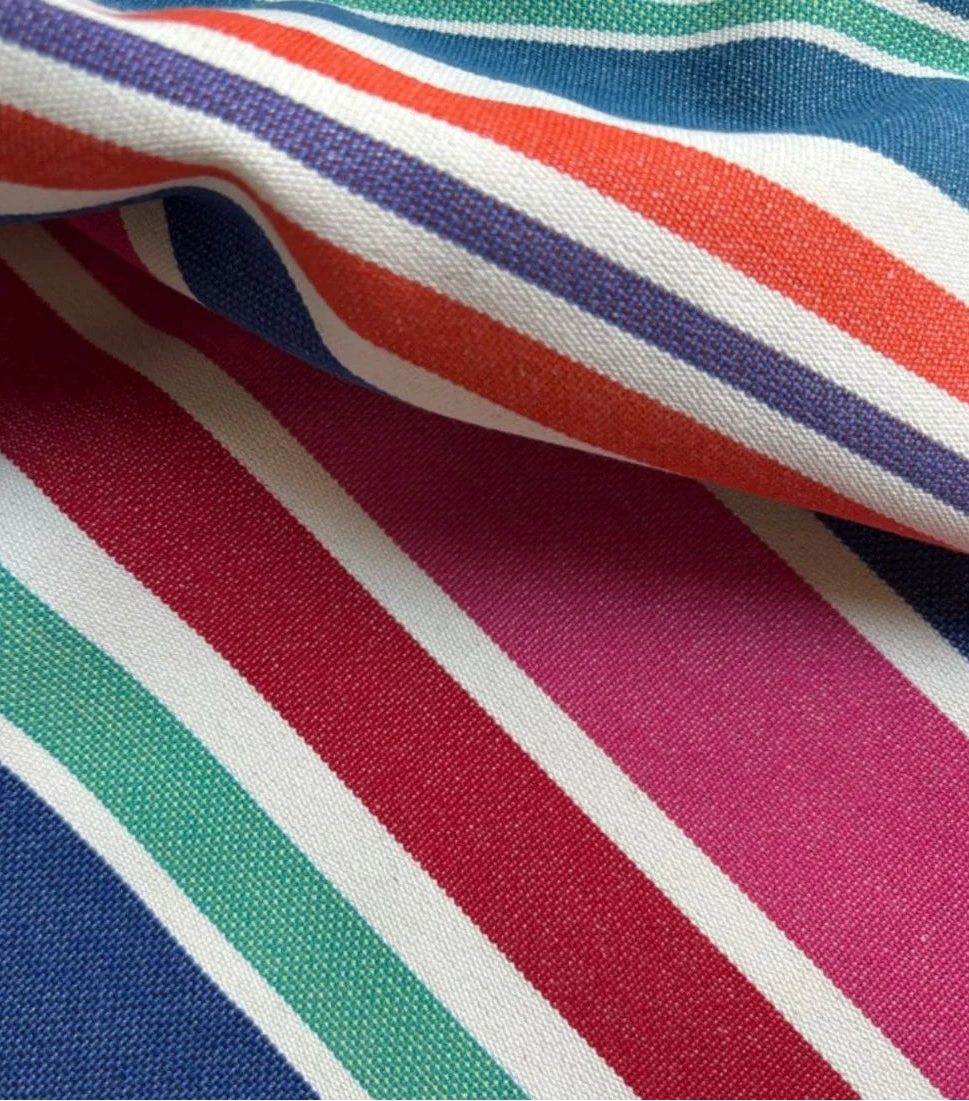 Close up of cotton fabric range-Aigue Marine, which is a multi coloured striped fabric made by Les toiles du Soleil. It showcases a variety of shades of blue, pink, red turquoise, greens and other vibrant colours