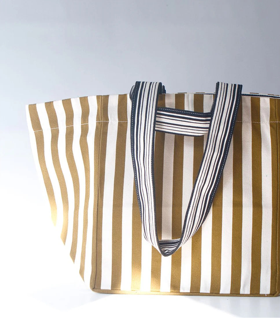 Photo of a tote bag with sun shining on it. The bag fabric is ecru/natural and bronze/khaki stripes