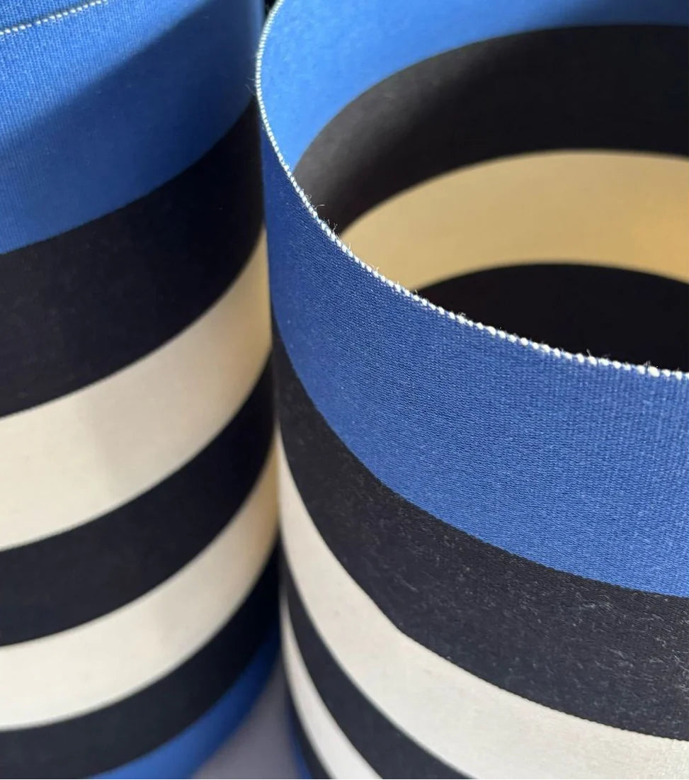 Close up of carthage Roy fabric. A bold cotton fabric featuring black and off- white, natural coloured stripes in between marine blue edges. Made by Les Toiles du Soleil