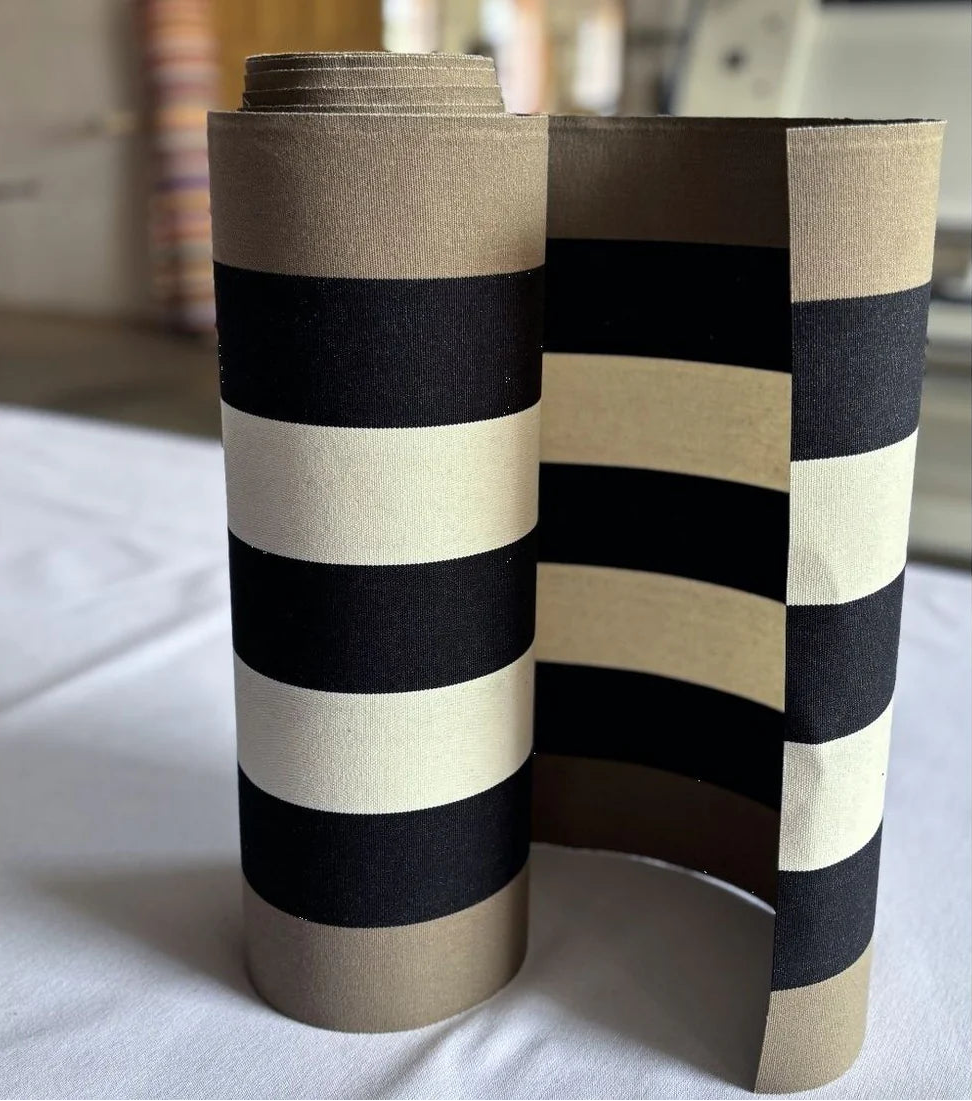 Close up of cotton fabric featuring bold black, ecru stripes in-between taupe coloured stripes on the edges