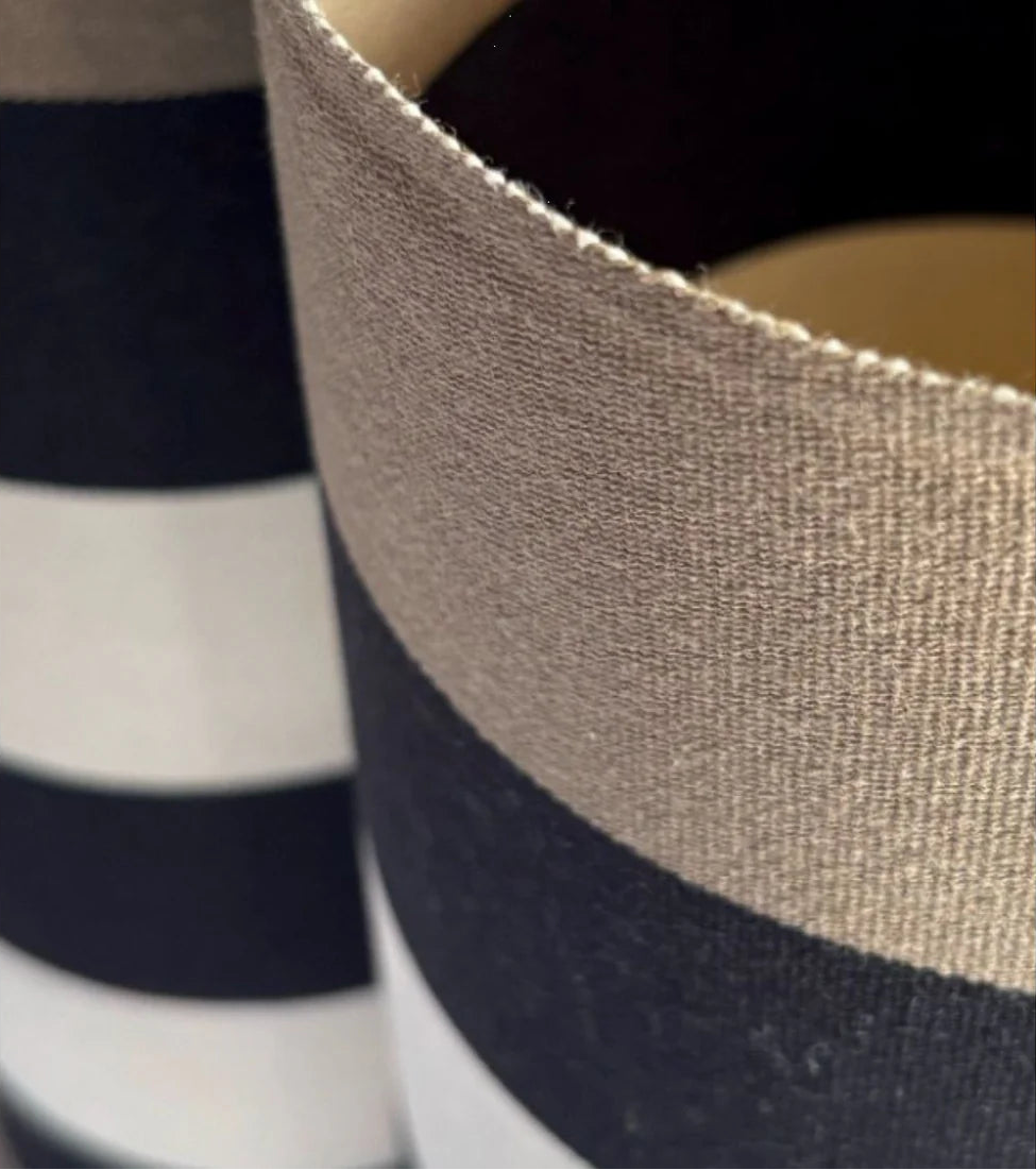 Close up of cotton fabric featuring bold black, ecru stripes in-between taupe coloured stripes on the edges