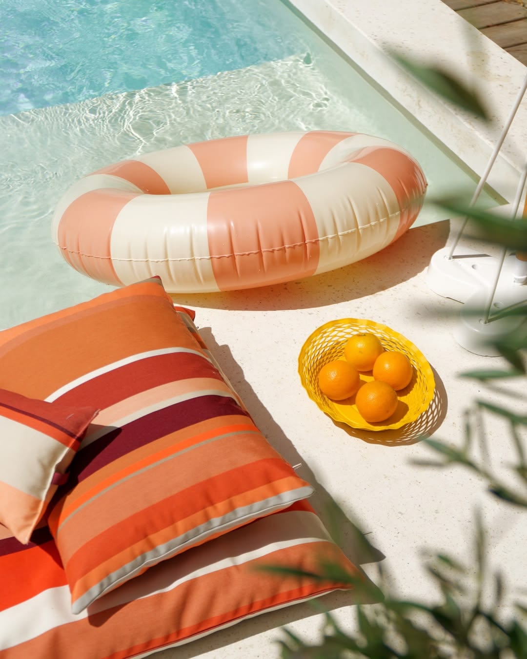 Pool side setting with cushions made from  Cayrou Les Toiles du Soleil Sunbrella outdoor fabric. Multi coloured striped fabric with shades of terracotta and warm tones