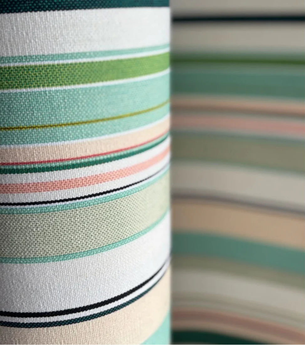 Close up of Bompas cotton fabric roll by Les Toiles du Soleil. Featuring soft hues of striped greens, turquoise, blush pink and white.