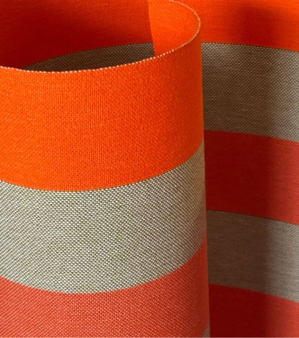 Close up of Carthage Tomette Orange fabric roll featuring a bold stripes of red, orange red, and beige/brown. A detailed 100% cotton weave by By Les Toiles du Soleil