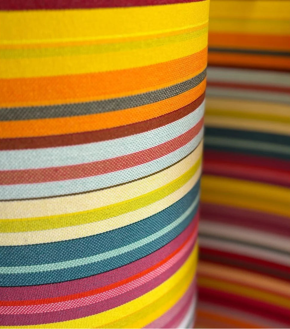 Close up of colourful striped fabric roll. Featuring thin strips of yellow, purple, blue, orange and other vibrant colours