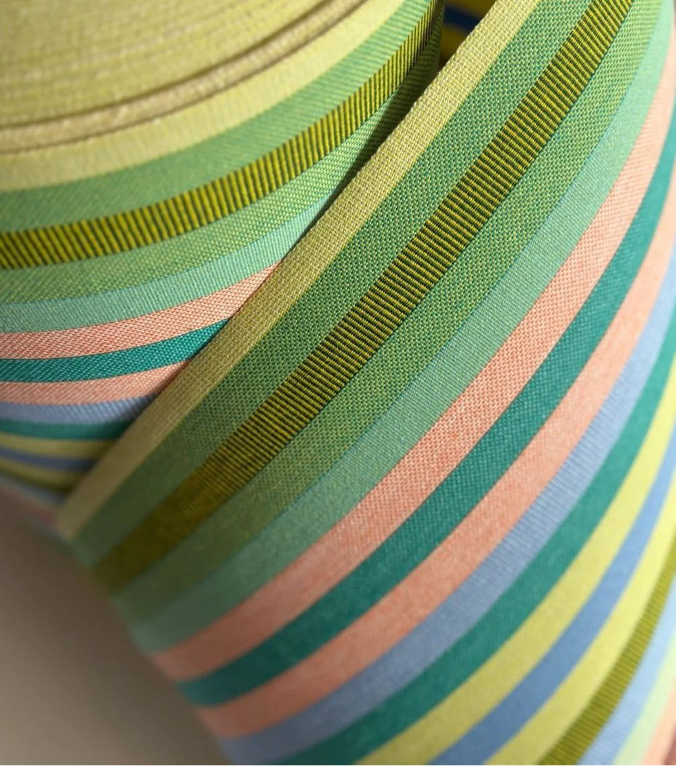 Close up of Pop Vert cotton fabric roll featuring teal, pink, blue, green, turquoise, and other vibrant coloured stripes.