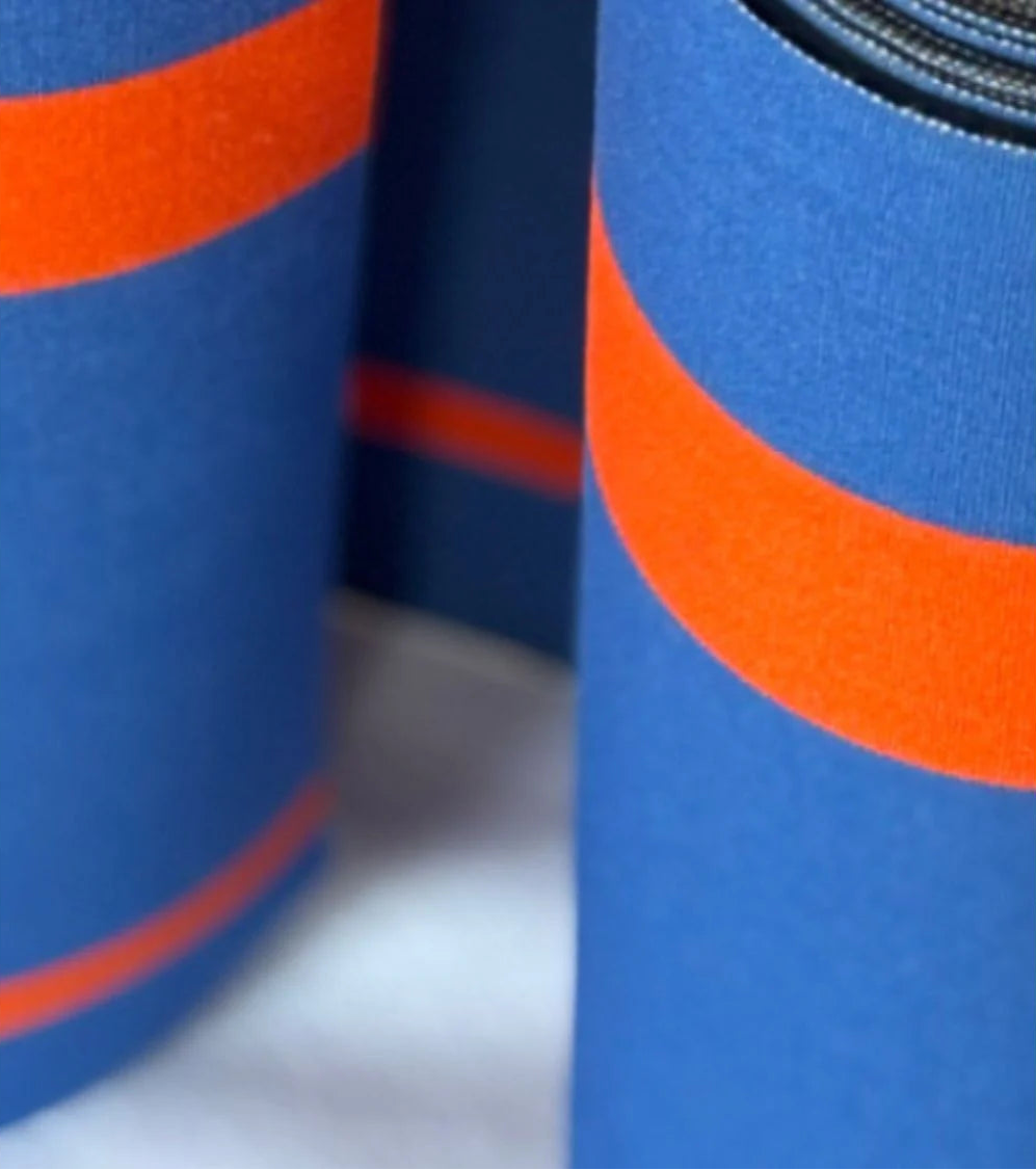 Close up of Rue du Soleil cotton fabric roll in vivid cobalt blue with fine bright orange accent stripes. Made by Les Toiles do Soleil. 