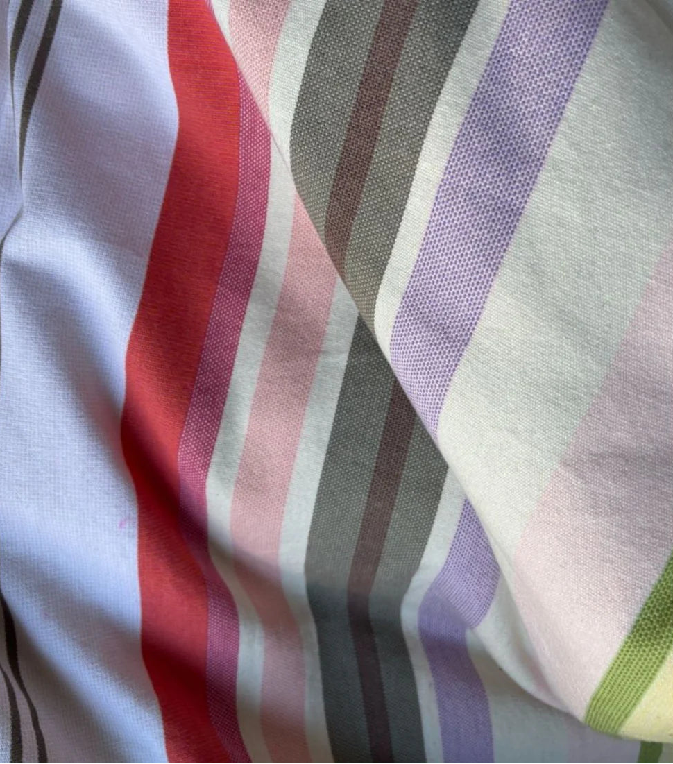 Close up of Sakura striped Les Toiles du Soleil 100% cotton fabric. Soft tones of white, beige, and blush pink reflect the gentle arrival of spring.