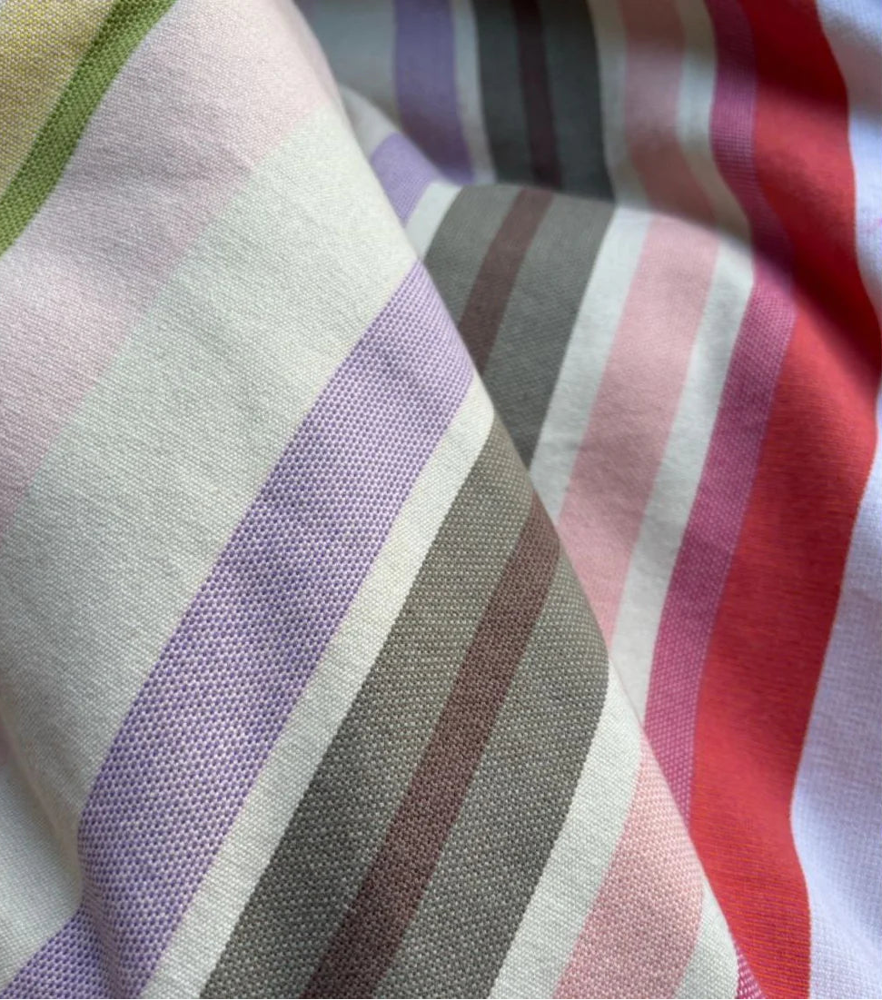 Close up of Sakura striped Les Toiles du Soleil 100% cotton fabric. Soft tones of white, beige, and blush pink reflect the gentle arrival of spring.