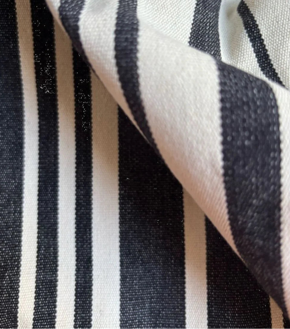 Close up of roll of 180cm cotton fabric by Les Toiles du Soleil called Tom Black. A multi striped pattern of white and black - like a barcode