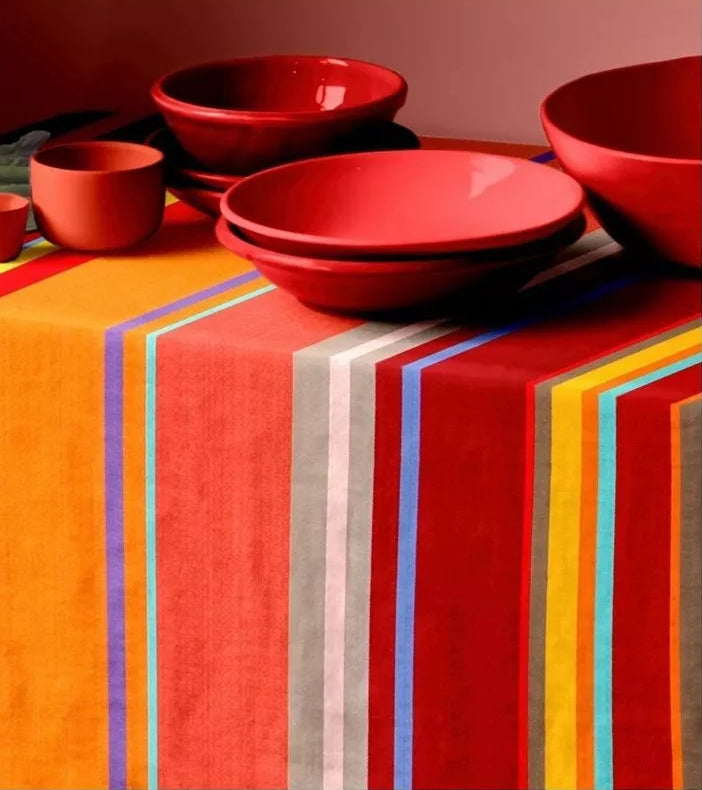 Red ceramic bowls on a table coth made from Collioure Rouge a Les Toiles du Soleil striped indoor fabric in red, orange, and yellow