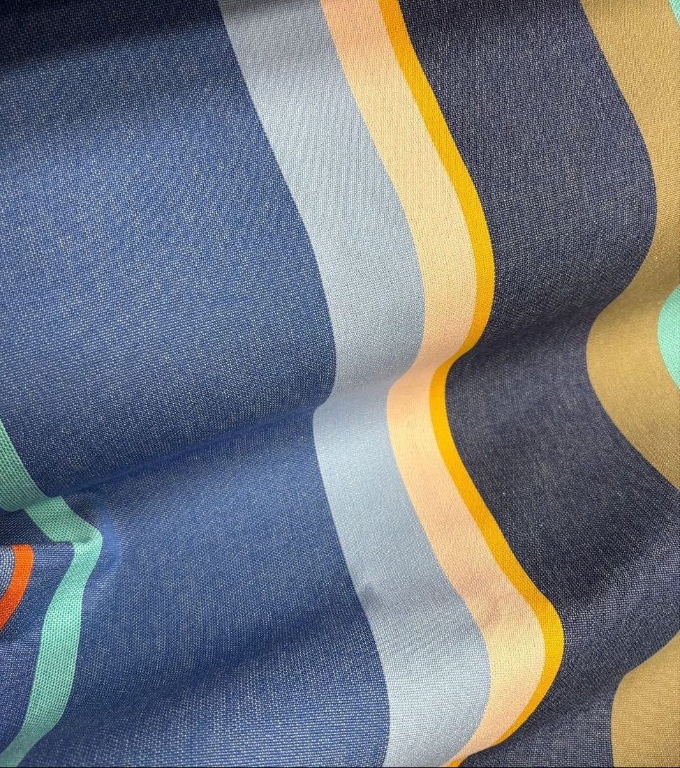 Close-up of Collioure Roy 100% cotton  Les toiles du Soleil fabric roll. Multi coloured striped with blues shades, yellow, and beige
