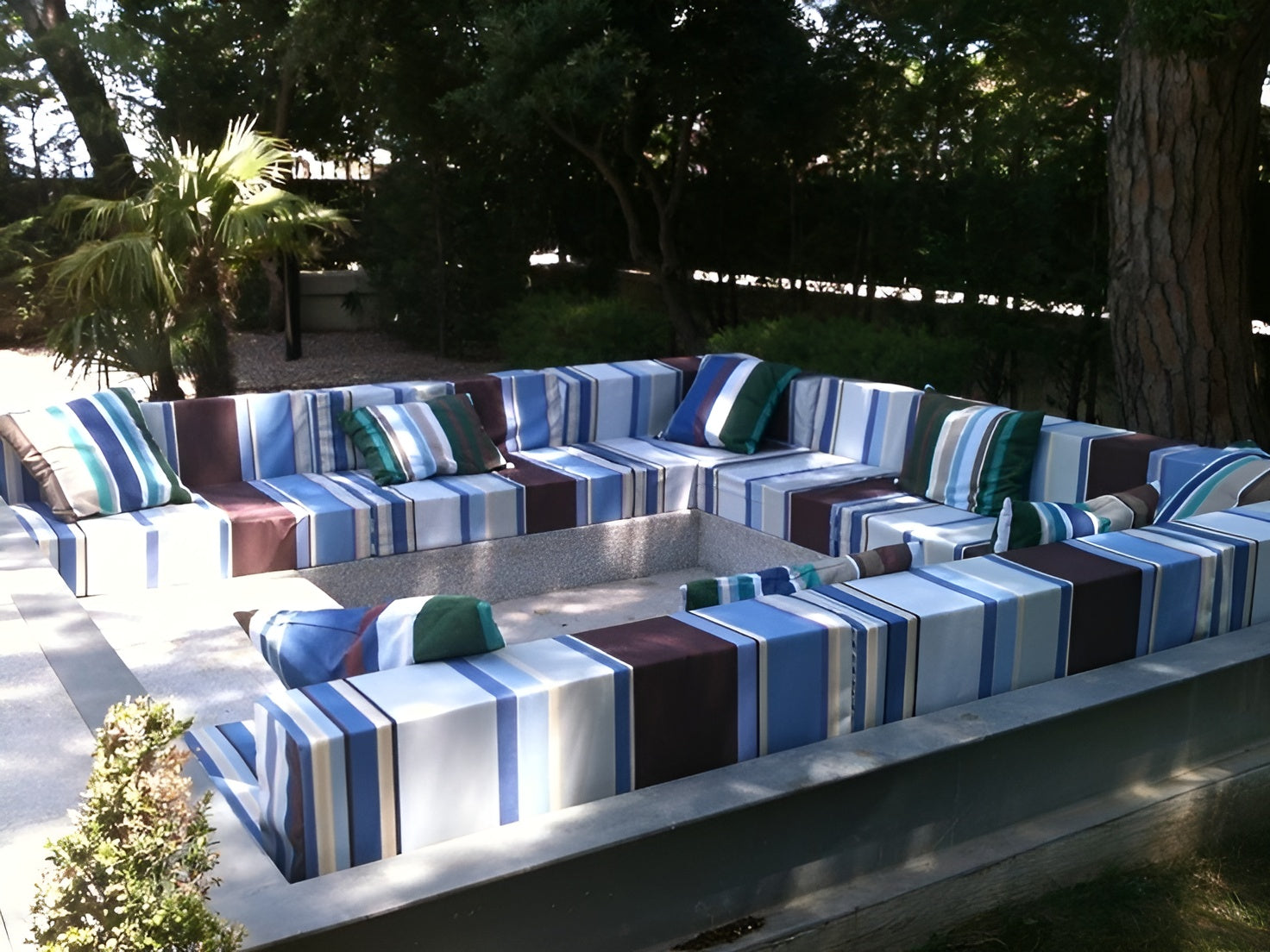 Outdoor patio furniture set with Les Toiles du Soleil Cyprian Outdoor Sunbrella Fabric striped cushions on a patio area.