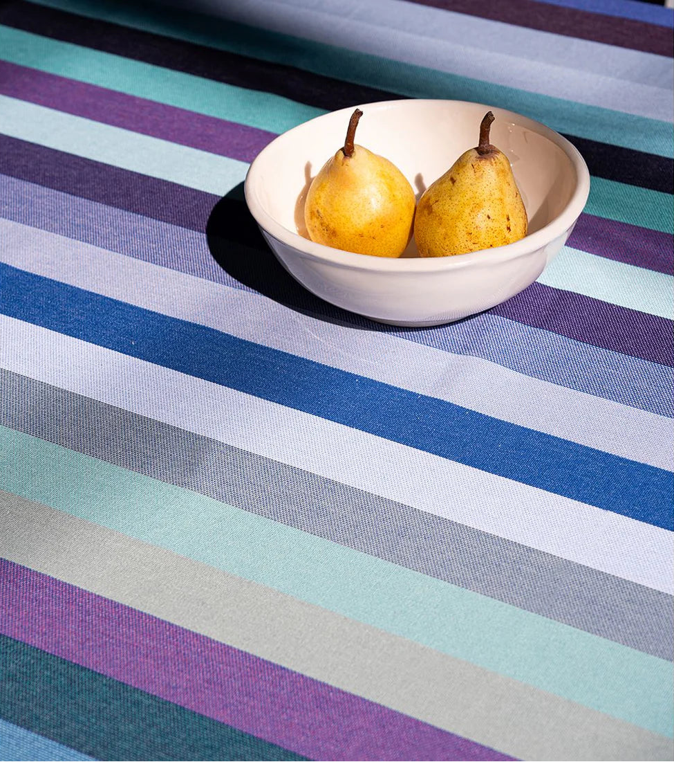 A Dani striped multi-coloured table cloth with a white bowl holding 2 pears. 