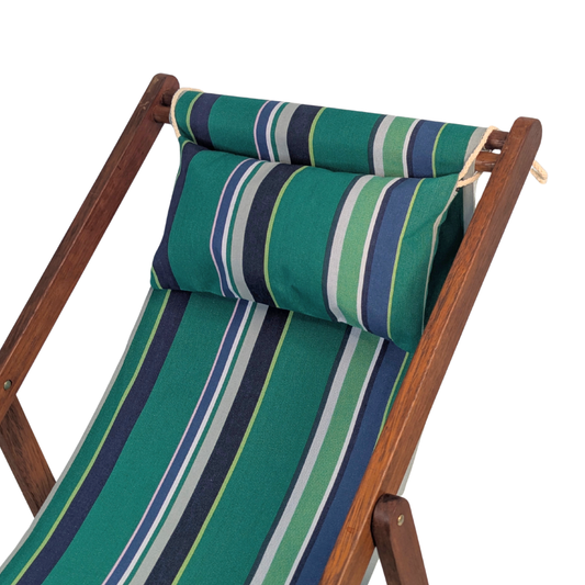 A wooden folding deck chair with a striped cotton fabric with bold stripes in deep teal, turquoise, and multiple shades of blue and green and matching headrest pillow, shown on a plain white background.