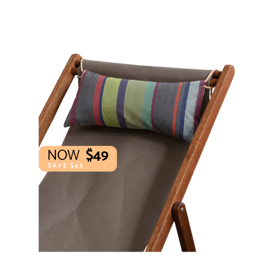 A striped lumbar pillow in muted green, blue, purple, and red tones, resting on the backrest of a brown wooden folding lounge chair with taupe fabric. A peach promotional badge reading 'NOW $49 SAVE $43' is overlaid on the lower left.