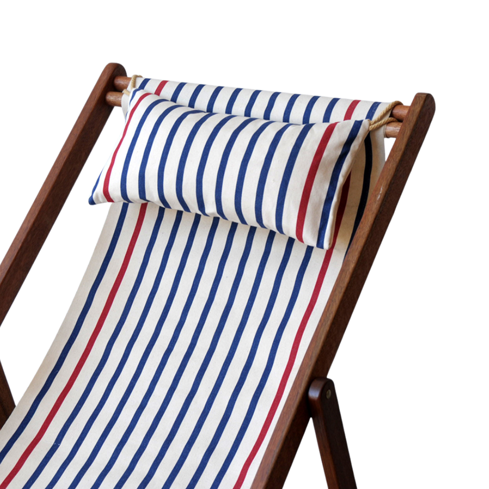 A striped head cushion on a wooden deckchair, featuring red and blue stripes with a white background.