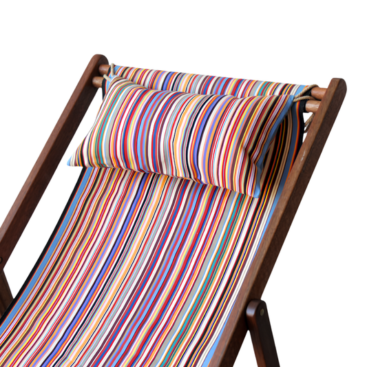 A multicoloured striped head cushion placed on a wooden deck chair.