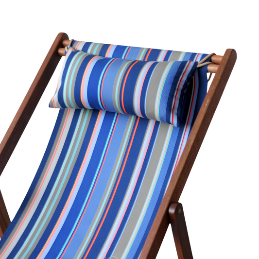 A striped head cushion placed on a wooden deckchair, featuring a vibrant pattern of blue, orange, grey, and turquoise.