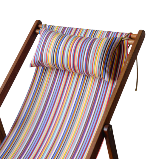 A striped head cushion on a wooden deckchair, featuring a multicolour pattern.