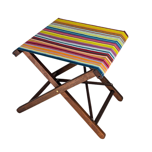 Hardwood folding stool with Les Toiles du Soleil multicoloured striped waterproof sunbrella fabric. Featuring an array of yellow, teal, orange, green, crimson, and more vibrant colours. Placed on a white background