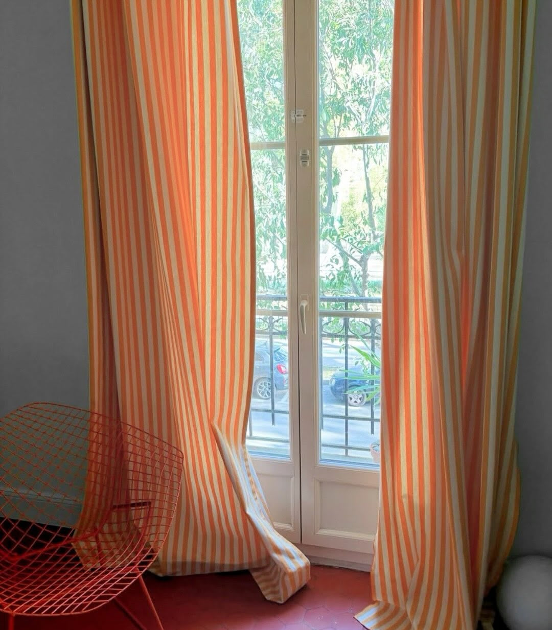 Isola Bella Les Toiles du Soleil yellow and white striped curtains hanging in front of a glass door with a view of trees.