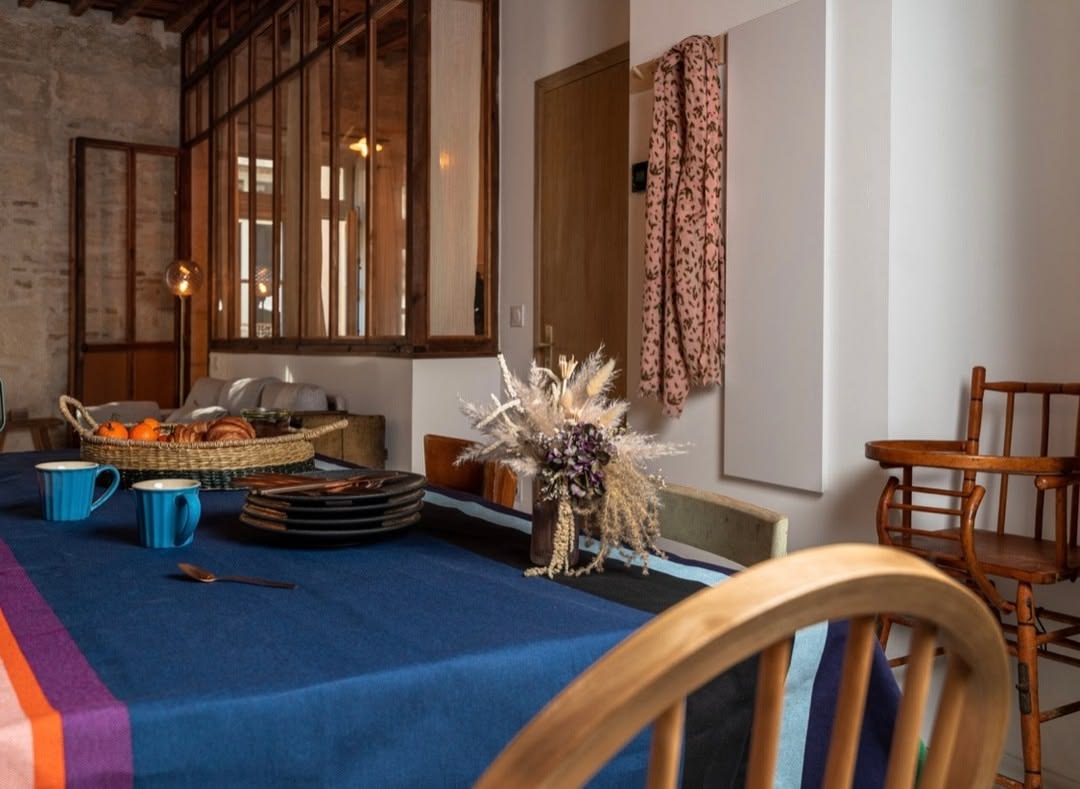 Dining setting in rustic room with cotton fabric Tablecloth of Lucas a fabric bold striped Les Toiles du Soleil woven fabric of deep purple, blush pink, burnt orange, petrol blue, black and forest green 