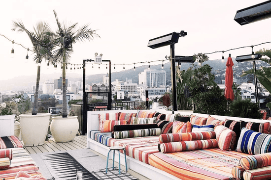 Colorful outdoor custom Les Toiles du Soleil furniture set on a rooftop with cityscape in the background