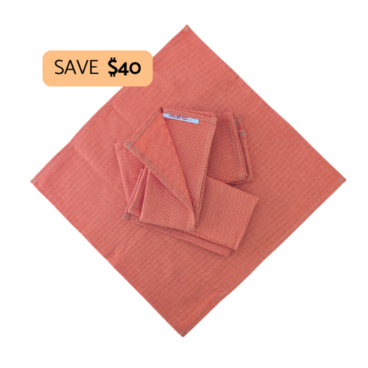 A set of textured fabric cloths in a warm orange color, including one unfolded cloth and several folded pieces stacked on top. A peach-colored promotional badge in the top-left corner reads 'SAVE $40'.