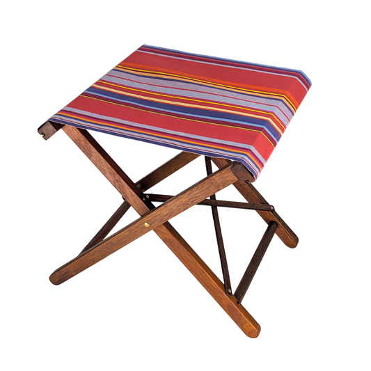 Hardwood folding stool with colourful multi-striped cotton fabric showcasing vibrant pinks, lavender, purple, yellow, and orange. Petit Sixtine is a fabric made by Les Toiles do Soleil. Placed on a white background