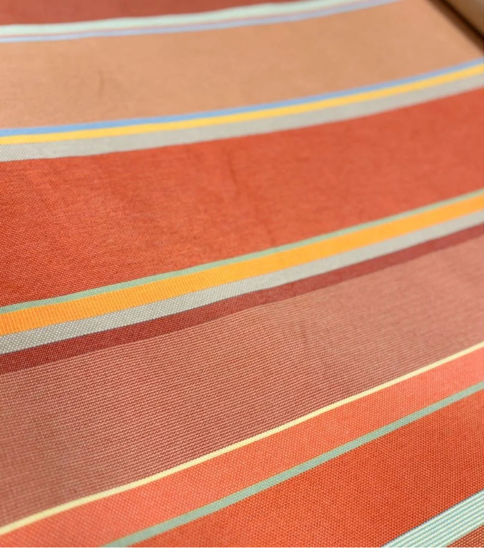 Close up photo of Les Toiles du Soleil 100% cotton Pezilla-la-rivière fabric roll. Striped with Multi colours - ight stone and terracotta, soft greens, subtle rusts and the patinated reds.