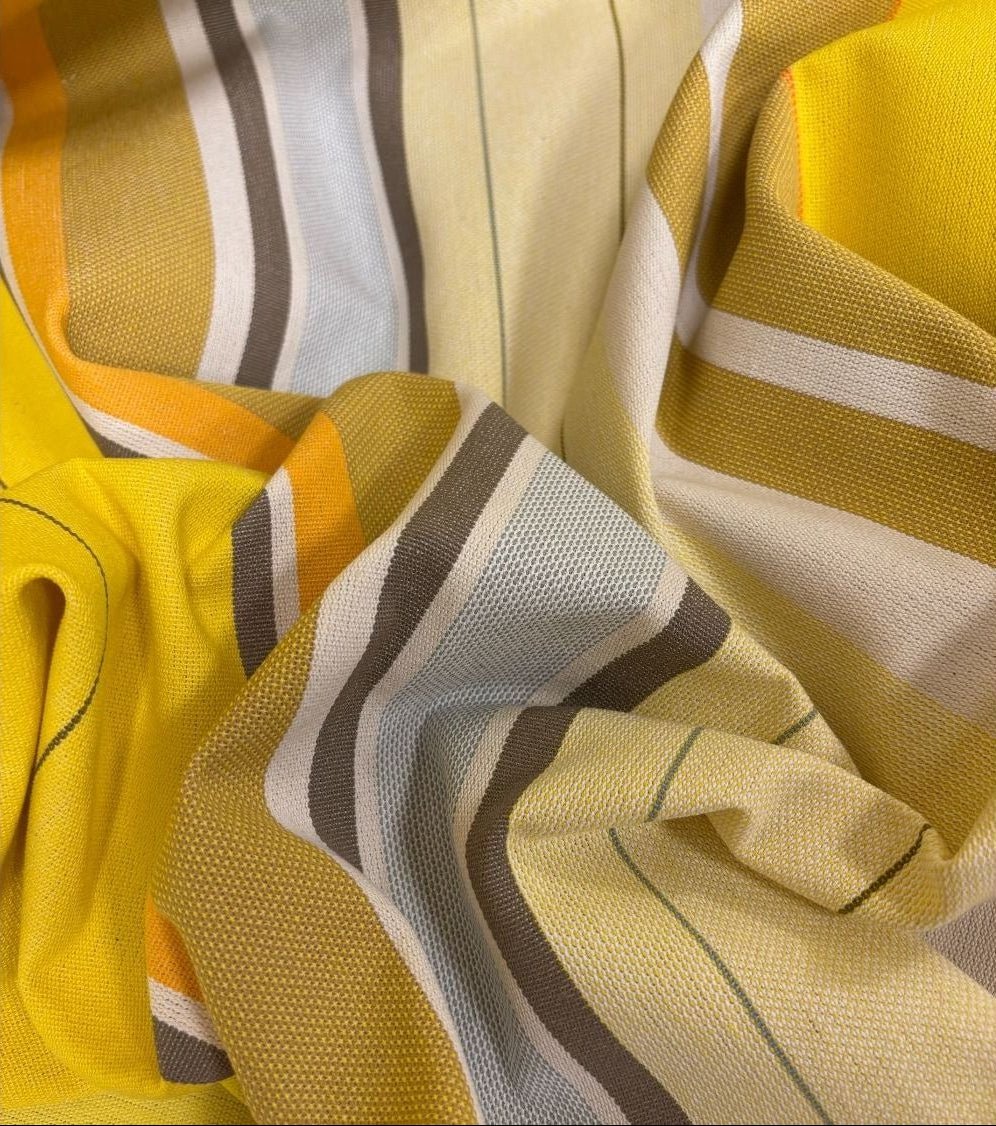 Close up of Plein Soleil multi coloured yellow, grey, and sun toned striped Les Toiles du Soleil 100% cotton fabric. 