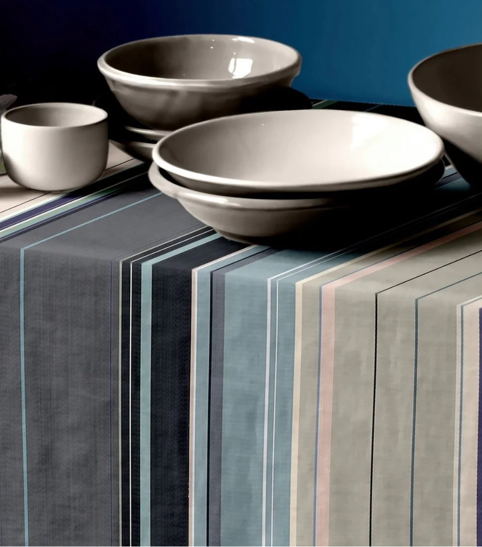 Tablecloth made from 100% cotton Les Toiles du Soleil fabric roll of Rue du Bac Gris - a multi striped woven pattern of different shades of greys, blues and beige. On top of the tablecloth are white ceramic bowls