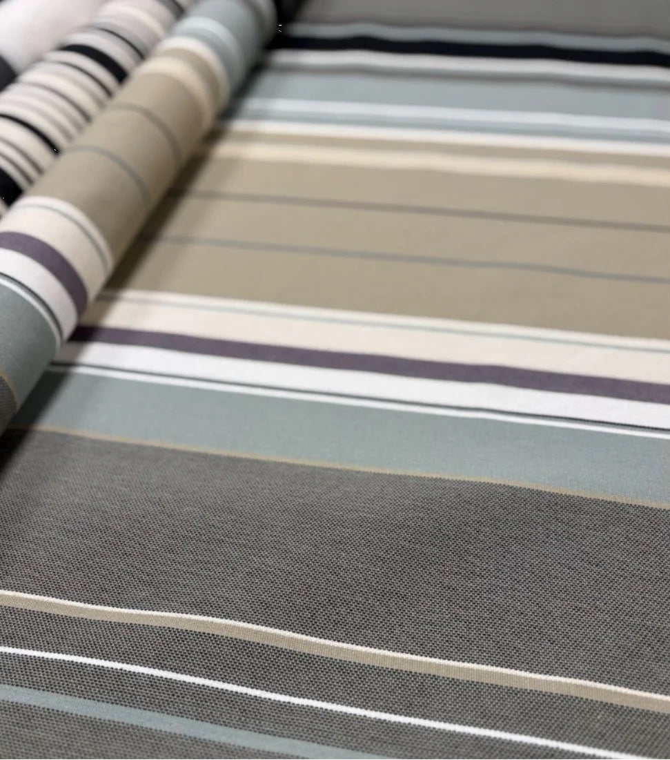 Close up of 100% cotton Les Toiles du Soleil fabric roll of Rue du Bac Gris - a multi striped woven pattern of different shades of greys, blues and beige