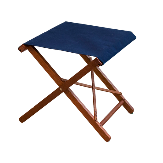 Ici et la folding stool with a hardwood frame and a solid navy blue synthetic Sunbrella fabric seat.