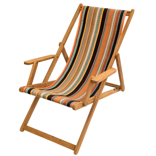 A teak deck chair with arms featuring a cotton striped fabric sling seat made by Les Toiles du Soleil in orange, black, beige, and green, shown on a plain white background. 
