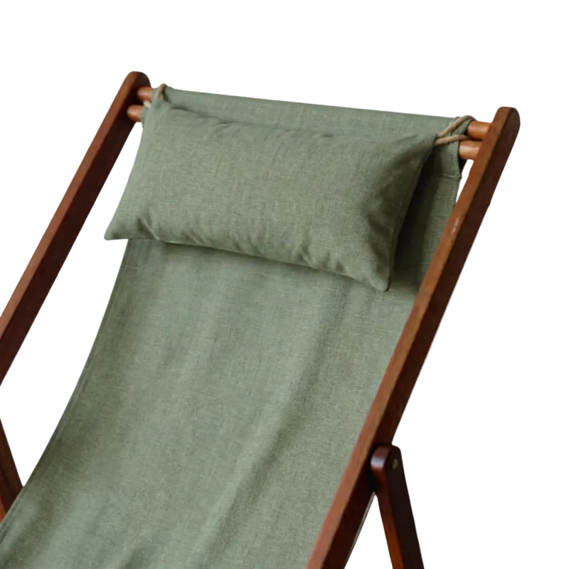A wooden folding deck chair with a green Sage Chilé fabric sling seat and back, featuring a matching navy blue headrest pillow secured by white rope ties, shown against a plain white background.