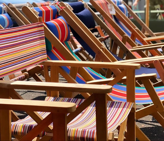 Row of colourful ici et la striped deck chairs on a street