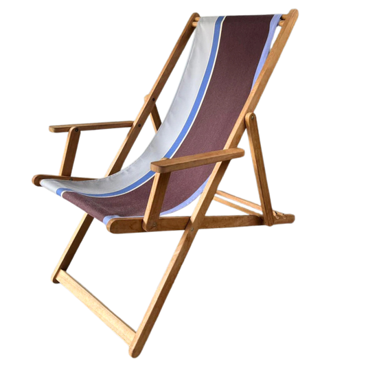 A teak wooden folding deck chair with arms featuring Les Toiles du Soleil Sunbrella fabric in a brown, white, and blue striped pattern, isolated on a white background.